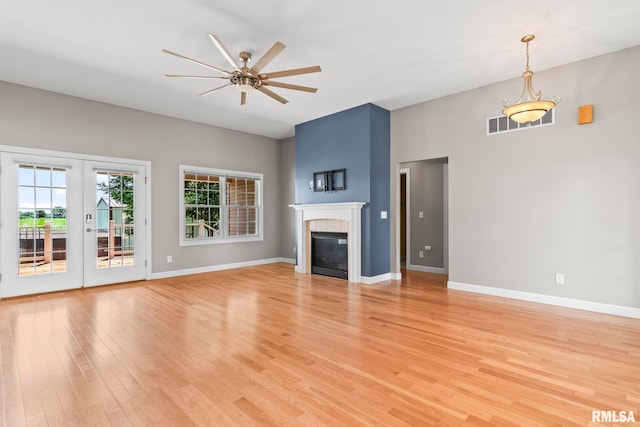 401 Cherry Cir, Williamsville, IL 62693 - unfurnished living room with a ceiling fan, light wood finished floors, a tiled fireplace, and french doors