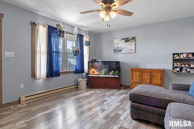 19581 Finney Rd, Girard, IL 62640 - sitting room with a baseboard radiator, wood finished floors, ceiling fan, and a textured ceiling