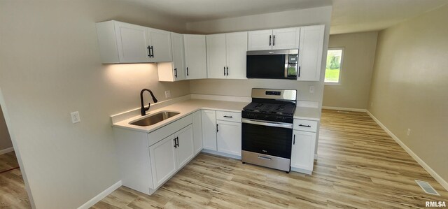 2217 Ramsey Ave, Springfield, IL 62702 - kitchen with stainless steel appliances, light wood-style floors, light countertops, and white cabinets