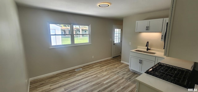 2217 Ramsey Ave, Springfield, IL 62702 - kitchen featuring light countertops, light wood-style floors, range with gas cooktop, and white cabinetry