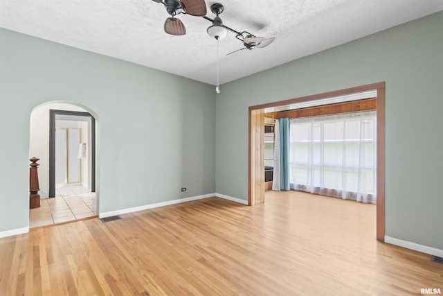508 N Washington St, Mount Pulaski, IL 62548 - empty room featuring ceiling fan, arched walkways, light wood-type flooring, and a textured ceiling
