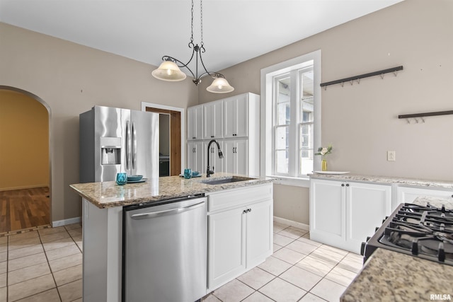 508 N Washington St, Mount Pulaski, IL 62548 - kitchen featuring appliances with stainless steel finishes, light tile patterned floors, arched walkways, white cabinets, and decorative light fixtures