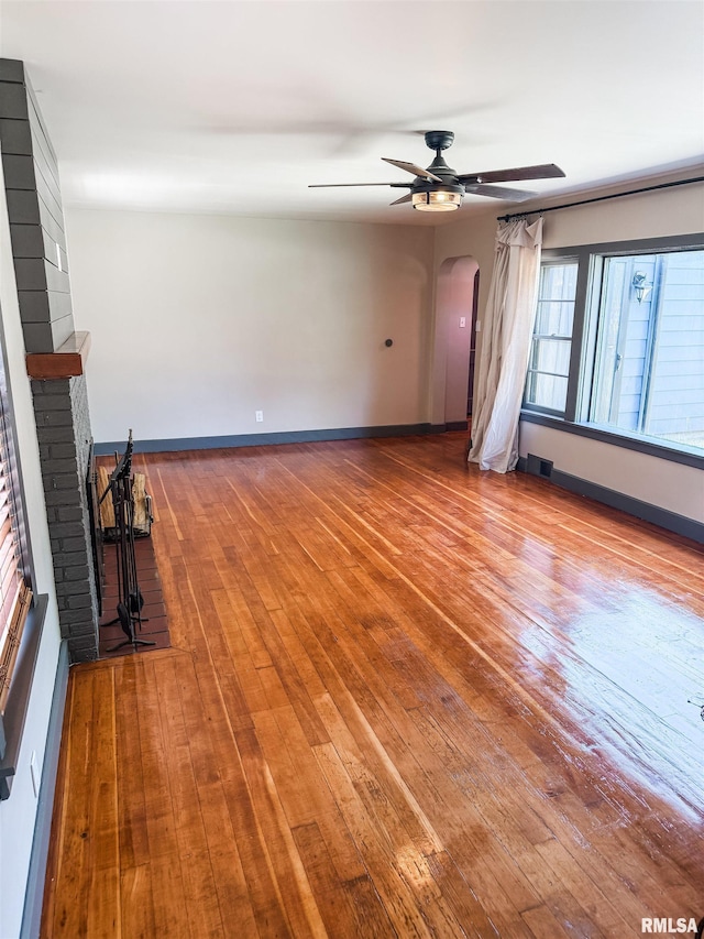 1011 S 20th St, Quincy, IL 62301 - unfurnished living room featuring ceiling fan, arched walkways, a brick fireplace, and wood-type flooring