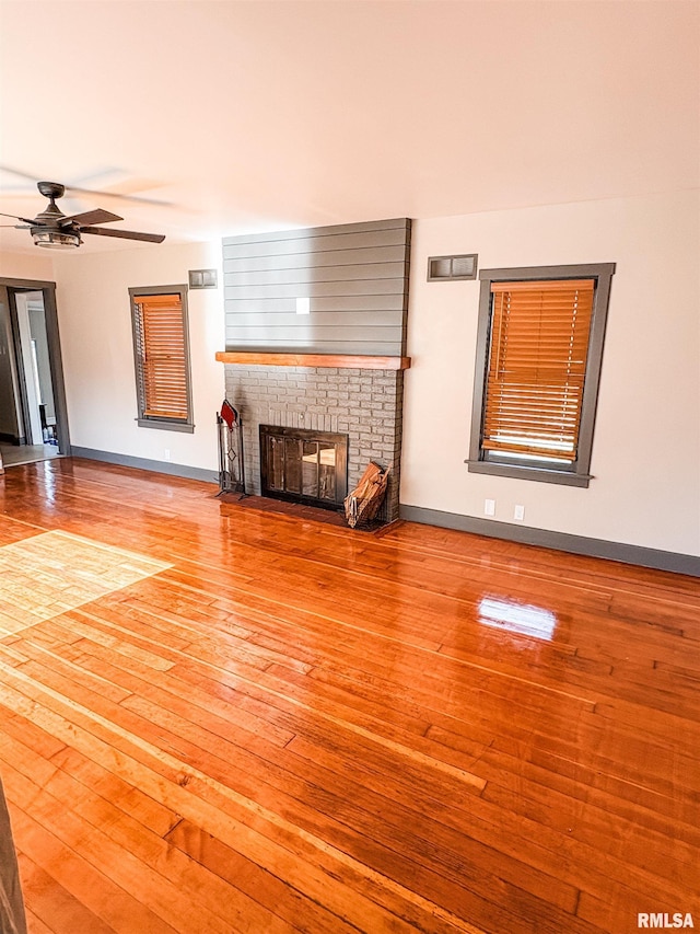 1011 S 20th St, Quincy, IL 62301 - unfurnished living room featuring wood-type flooring, a brick fireplace, and ceiling fan