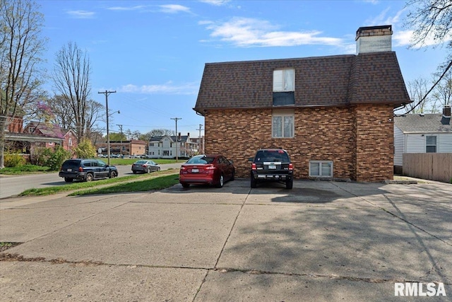 102 W Scarritt St, Springfield, IL 62704 - view of property exterior with brick siding, mansard roof, roof with shingles, and uncovered parking