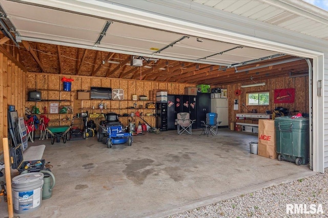 1640 W Glenn Ave, Springfield, IL 62704 - garage featuring freestanding refrigerator, wooden walls, and a garage door opener