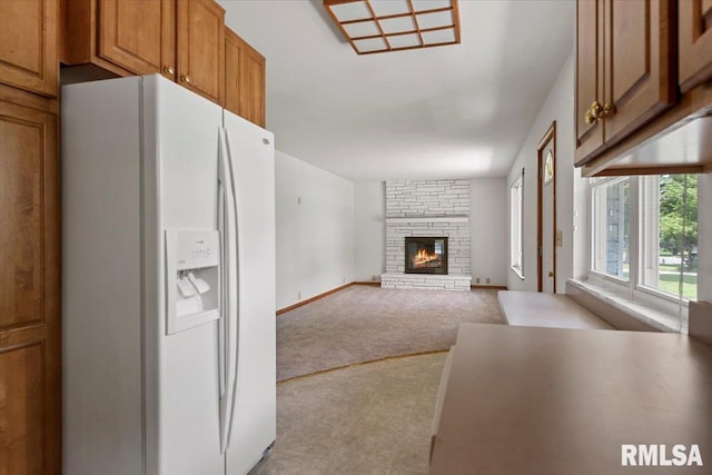 1640 W Glenn Ave, Springfield, IL 62704 - kitchen featuring white refrigerator with ice dispenser, a stone fireplace, brown cabinetry, carpet flooring, and open floor plan