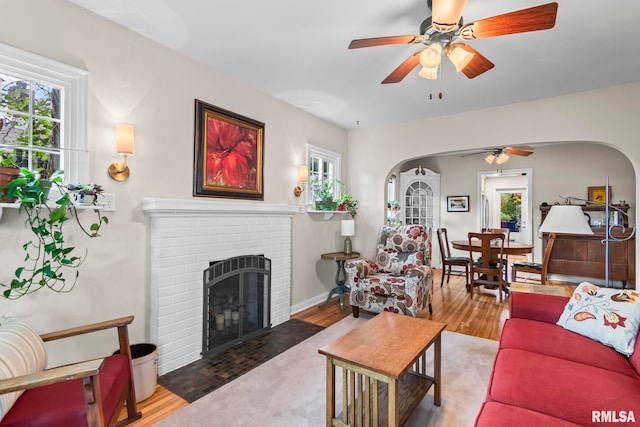 1935 S Douglas Ave, Springfield, IL 62704 - living room featuring arched walkways, a ceiling fan, wood finished floors, and a brick fireplace