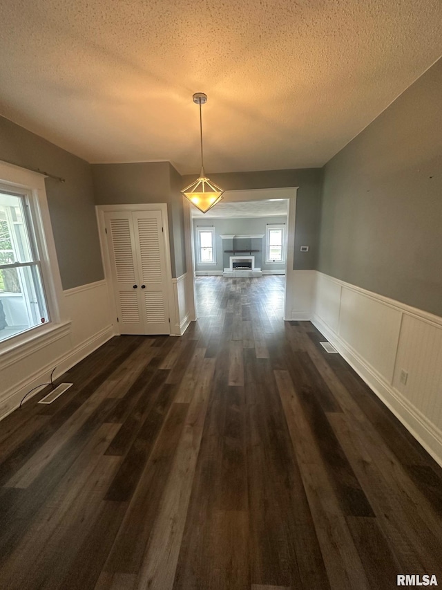 1249 W Urban Ave, Springfield, IL 32704 - unfurnished dining area featuring dark wood-style floors, a textured ceiling, and a wainscoted wall