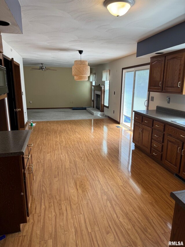 1804 Hunter Ridge Dr, Springfield, IL 62704 - kitchen featuring dark countertops, open floor plan, a fireplace with raised hearth, ceiling fan, and light wood finished floors