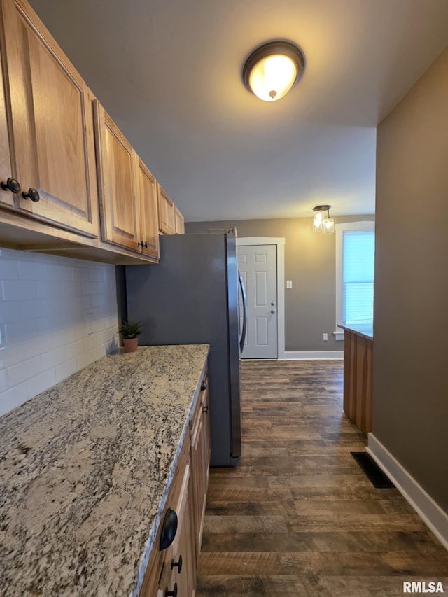 815 Washington St, Quincy, IL 62301 - kitchen with dark wood-style flooring, decorative backsplash, light stone counters, and freestanding refrigerator