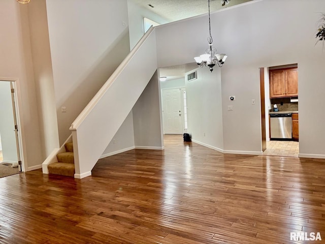 3205 Ashley Ln, Springfield, IL 62711 - unfurnished living room with a high ceiling, a chandelier, stairway, and light wood-style flooring