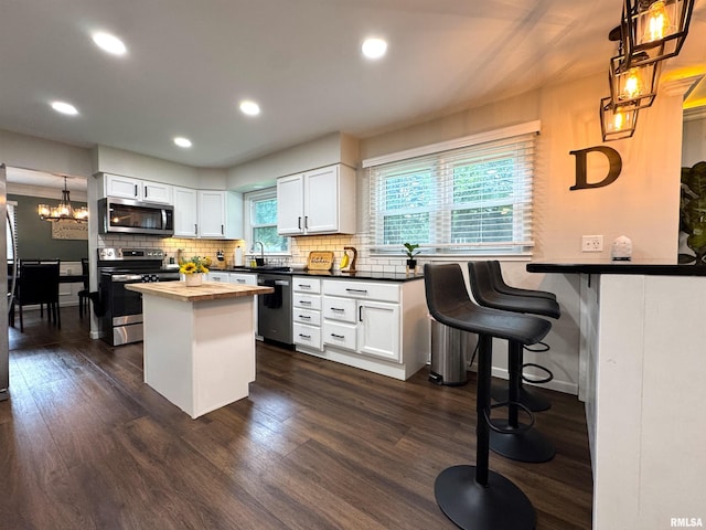 125 Pinehurst Dr, Springfield, IL 62704 - kitchen with appliances with stainless steel finishes, white cabinets, tasteful backsplash, dark wood-style floors, and a chandelier