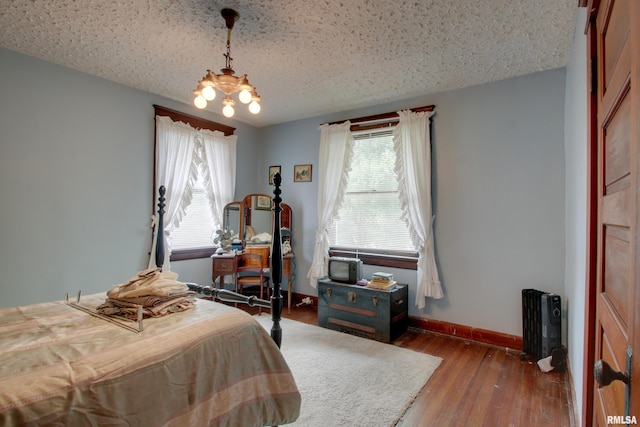 229 S 11th St, Quincy, IL 62301 - bedroom featuring multiple windows, radiator heating unit, a chandelier, wood-type flooring, and a textured ceiling