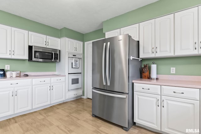 1860 Mayfield Rd, Chatham, IL 62629 - kitchen with appliances with stainless steel finishes, light countertops, white cabinets, and light wood-style flooring