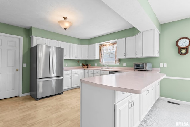 1860 Mayfield Rd, Chatham, IL 62629 - kitchen featuring freestanding refrigerator, a peninsula, light countertops, white cabinetry, and light wood-type flooring
