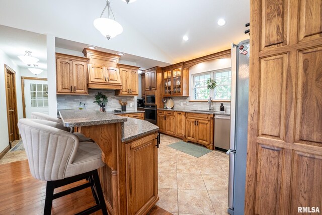 623 Jasper Rd, Centralia, IL 62801 - kitchen with appliances with stainless steel finishes, a breakfast bar area, lofted ceiling, decorative backsplash, and glass insert cabinets