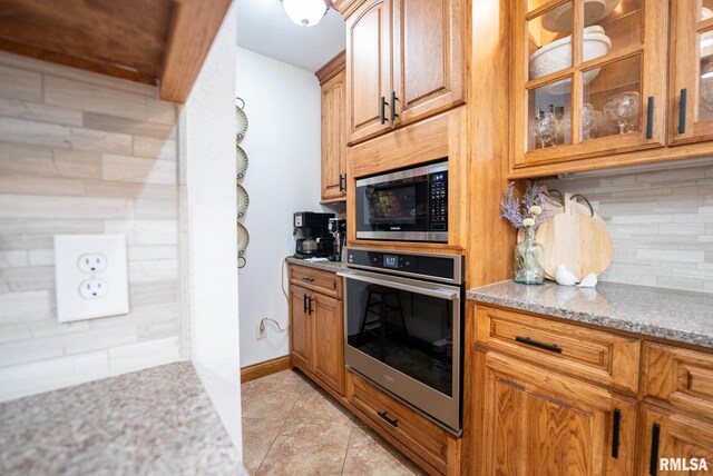 623 Jasper Rd, Centralia, IL 62801 - kitchen with stainless steel appliances, light stone countertops, glass insert cabinets, decorative backsplash, and light tile patterned floors