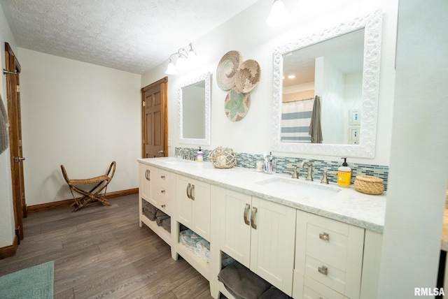 623 Jasper Rd, Centralia, IL 62801 - full bath featuring wood finished floors, double vanity, a textured ceiling, and decorative backsplash
