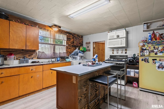 215 N Wilson St, Girard, IL 62640 - kitchen with white appliances, light wood finished floors, a center island, and a kitchen bar
