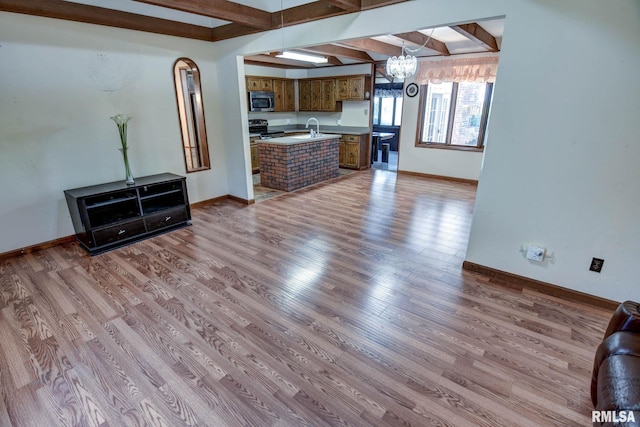 107 E Harrison St, Edinburg, IL 62531 - unfurnished living room with a chandelier, wood finished floors, and beamed ceiling