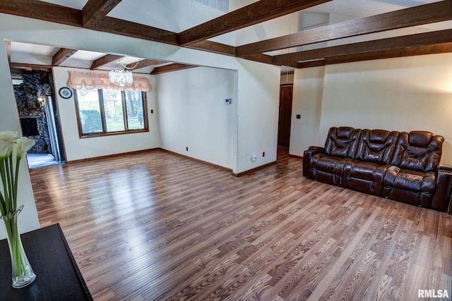 107 E Harrison St, Edinburg, IL 62531 - unfurnished living room with wood finished floors, beamed ceiling, a chandelier, and a fireplace