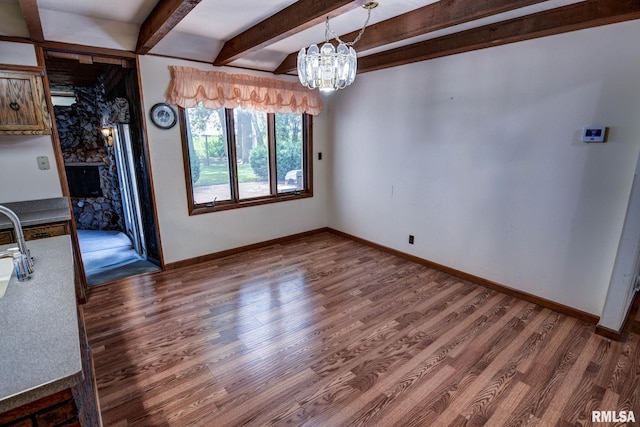 107 E Harrison St, Edinburg, IL 62531 - unfurnished dining area featuring wood finished floors, a chandelier, beamed ceiling, and a fireplace