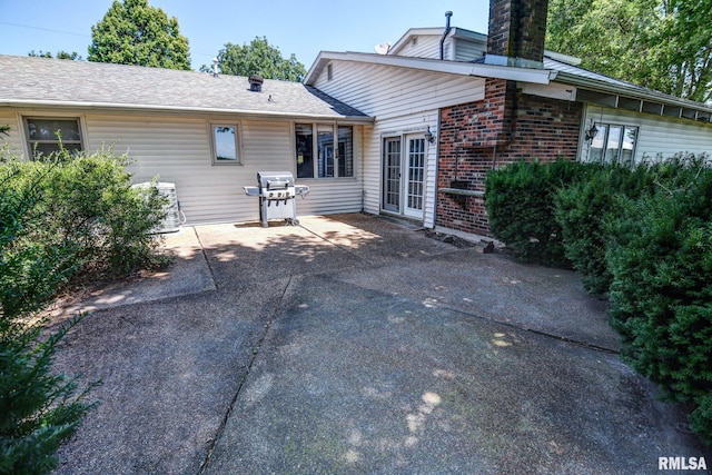 107 E Harrison St, Edinburg, IL 62531 - rear view of property featuring brick siding, a chimney, and a patio