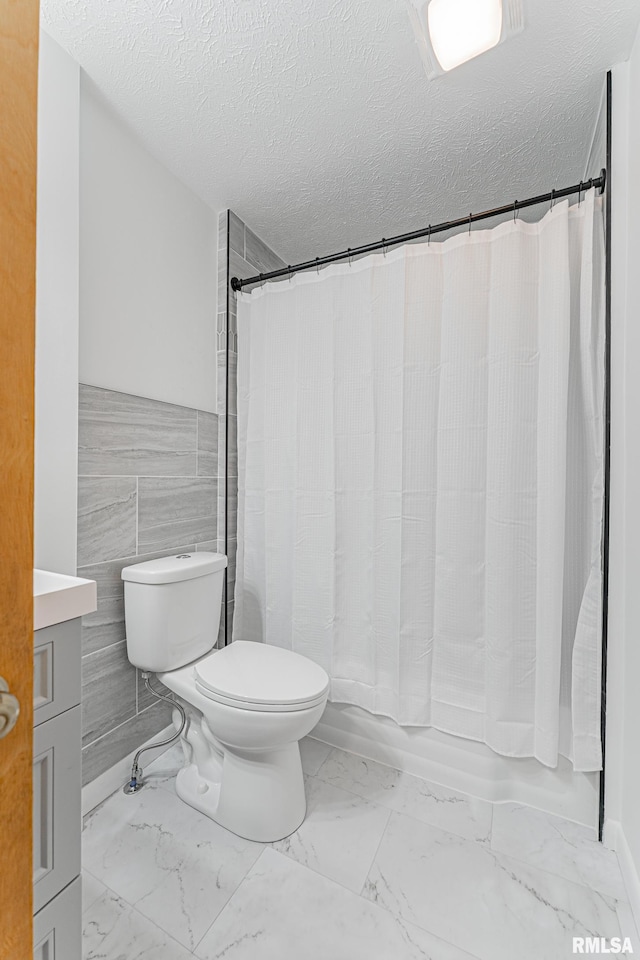 914 Pekin St, Lincoln, IL 62656 - full bath featuring marble finish floors, vanity, a textured ceiling, shower / tub combo, and tile walls