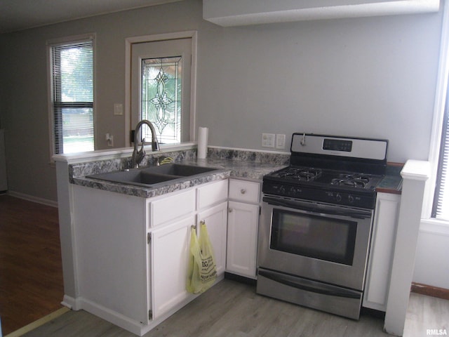 1346 Chestnut St, Quincy, IL 62301 - kitchen with stainless steel gas stove, a peninsula, light wood-style floors, and white cabinetry