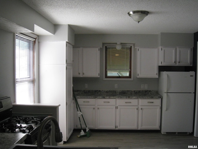 1346 Chestnut St, Quincy, IL 62301 - kitchen with freestanding refrigerator, gas range oven, white cabinetry, a textured ceiling, and light wood-type flooring