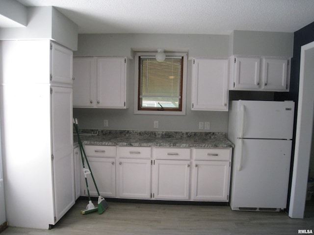 1346 Chestnut St, Quincy, IL 62301 - kitchen featuring freestanding refrigerator, white cabinets, light wood-style flooring, and a textured ceiling