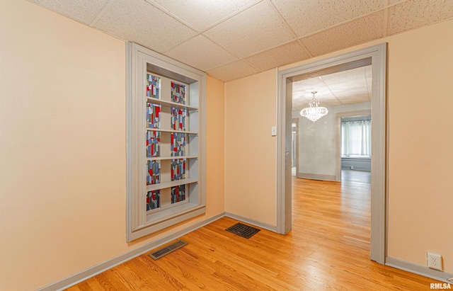 1231 Pulaski St, Lincoln, IL 62656 - empty room featuring a paneled ceiling, light wood-style floors, and a chandelier