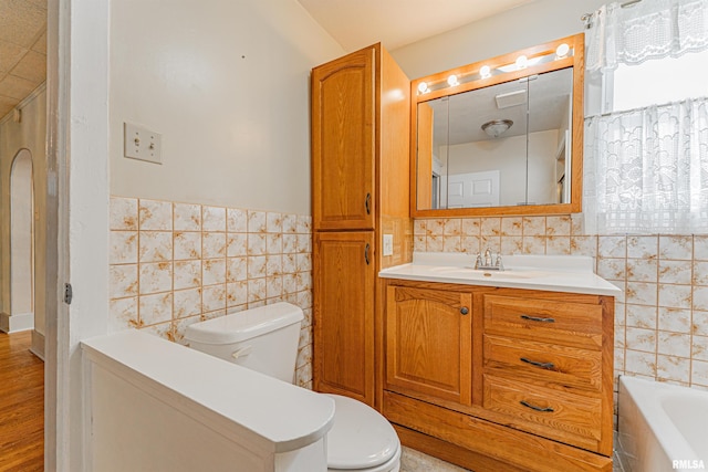 1231 Pulaski St, Lincoln, IL 62656 - full bathroom featuring tile walls, vanity, a tub to relax in, wood finished floors, and wainscoting