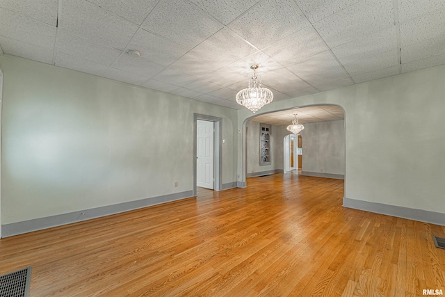 1231 Pulaski St, Lincoln, IL 62656 - spare room with arched walkways, wood finished floors, and a chandelier