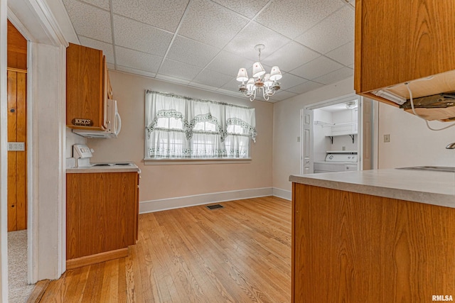 1231 Pulaski St, Lincoln, IL 62656 - kitchen with washer / dryer, a chandelier, white microwave, brown cabinetry, and light wood-style floors