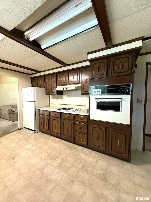 573 Matthews Ct, Oneida, IL 61467 - kitchen featuring white appliances, dark brown cabinets, light countertops, under cabinet range hood, and light flooring