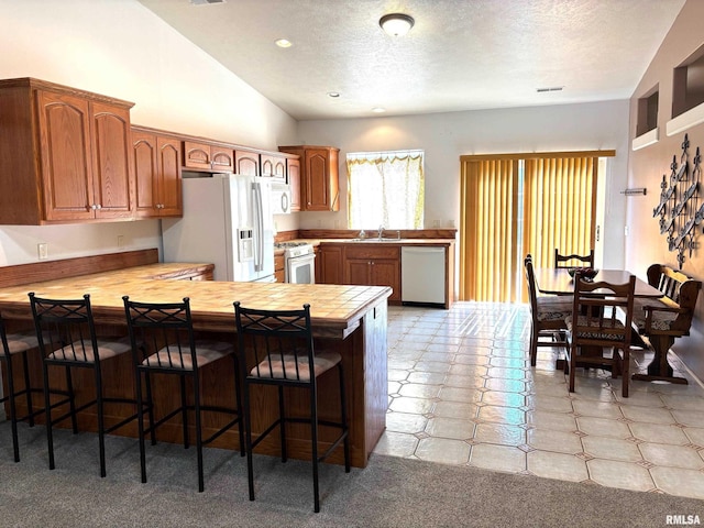4317 Harvard Dr, Springfield, IL 62712 - kitchen featuring white appliances, a peninsula, a breakfast bar, a textured ceiling, and lofted ceiling
