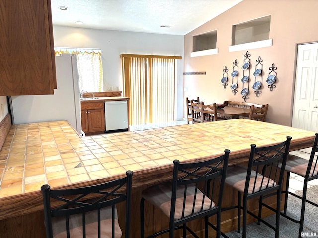 4317 Harvard Dr, Springfield, IL 62712 - kitchen with white appliances, lofted ceiling, tile counters, a breakfast bar, and brown cabinetry