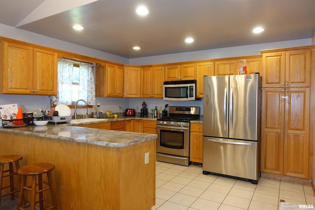 1156 Russell Ave, Galesburg, IL 61401 - kitchen with appliances with stainless steel finishes, a peninsula, light tile patterned flooring, brown cabinetry, and recessed lighting