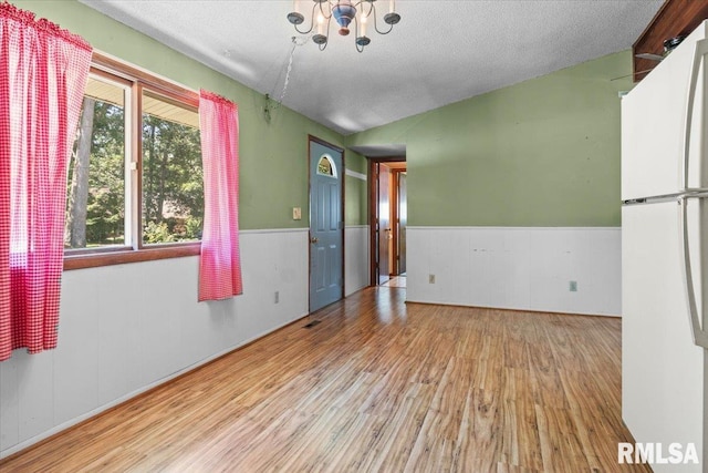 15858 Oak Ln, Girard, IL 62640 - spare room featuring a chandelier, wood finished floors, a wainscoted wall, lofted ceiling, and a textured ceiling