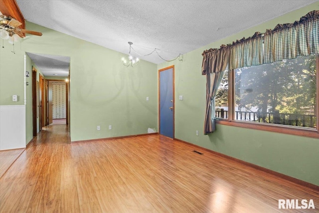 15858 Oak Ln, Girard, IL 62640 - empty room featuring vaulted ceiling, wood finished floors, a textured ceiling, a chandelier, and a ceiling fan