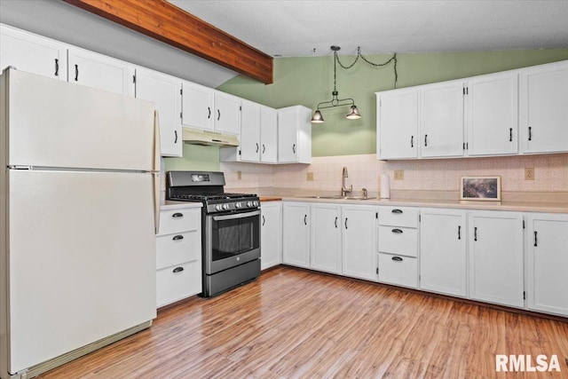 15858 Oak Ln, Girard, IL 62640 - kitchen with freestanding refrigerator, stainless steel gas range oven, under cabinet range hood, white cabinets, and light countertops