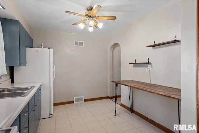 2912 E Enos Ave, Springfield, IL 62702 - kitchen with a ceiling fan, arched walkways, freestanding refrigerator, and blue cabinets
