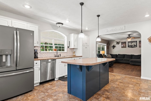 16540 Wernowsky St, Petersburg, IL 62675 - kitchen featuring appliances with stainless steel finishes, white cabinets, decorative backsplash, ceiling fan, and a kitchen island
