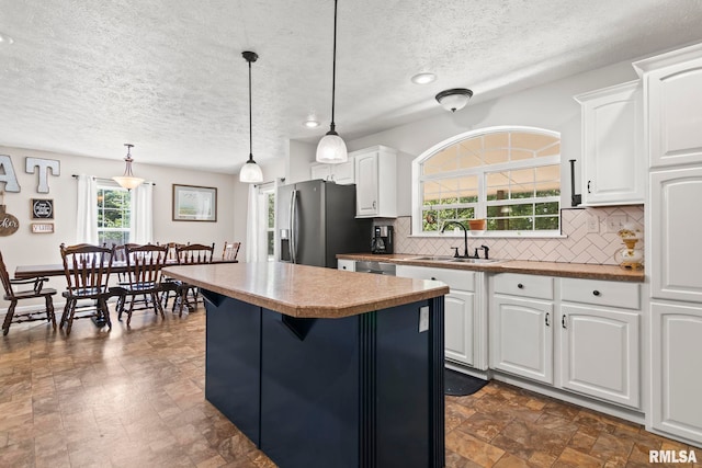 16540 Wernowsky St, Petersburg, IL 62675 - kitchen with stainless steel appliances, a textured ceiling, a kitchen island, decorative backsplash, and white cabinetry