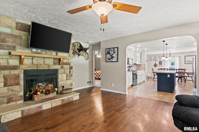16540 Wernowsky St, Petersburg, IL 62675 - living room featuring arched walkways, wood finished floors, a textured ceiling, ceiling fan, and a fireplace
