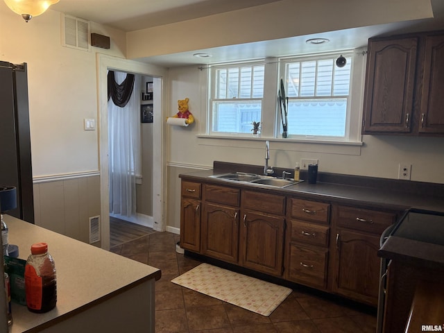 700 S 20th St, Quincy, IL 62301 - kitchen featuring dark tile patterned flooring, dark countertops, a wainscoted wall, and dark brown cabinetry