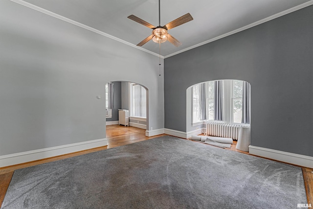 418 E Cooke St, Mount Pulaski, IL 62548 - spare room with arched walkways, wood finished floors, crown molding, a ceiling fan, and radiator