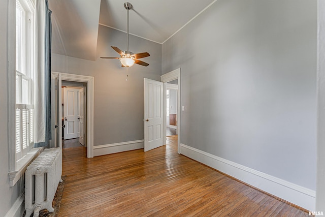 418 E Cooke St, Mount Pulaski, IL 62548 - spare room featuring radiator, high vaulted ceiling, a ceiling fan, and light wood-style flooring